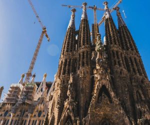 View of Sagrada Familia's intricate facade and cranes against a clear blue sky in Barcelona.