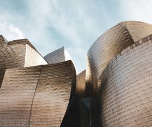 Low angle view of Guggenheim Museum Bilbao's modern architecture under a bright sky.